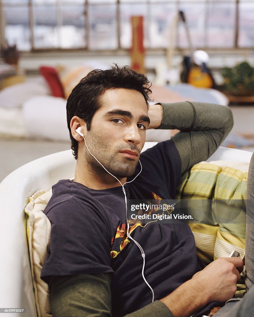 Man Sitting in an Empty Bath Listening to Music on an MP3 Player