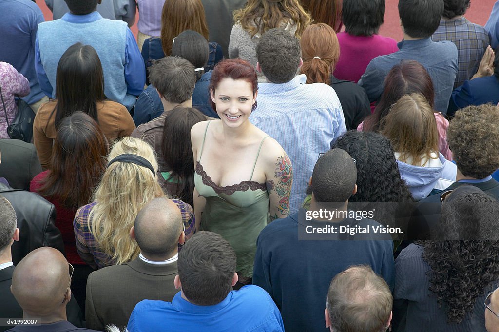 Young Woman with a Tattoo Standing Out From a Crowd of People with Their Back Turned