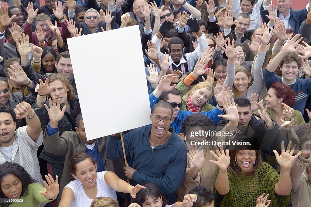 Large Crowd of People with Their Hands Raised in the Air with One Man Holding a Blank Placard