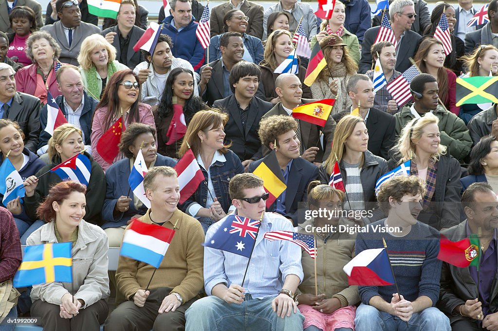 Large Group of People Sitting in Rows and Holding International Flags