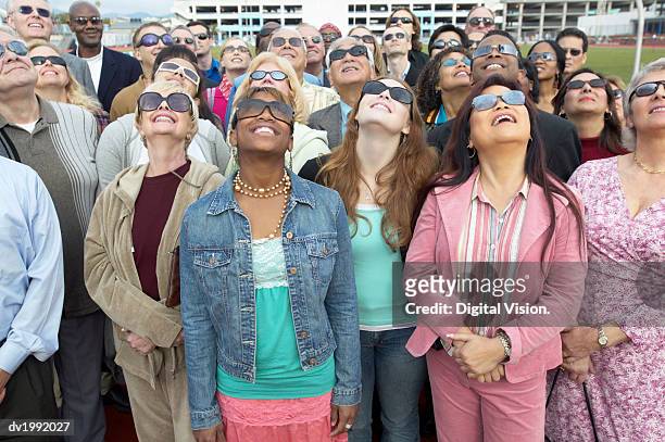 crowd standing wearing sunglasses looking up - solar eclipse stock pictures, royalty-free photos & images