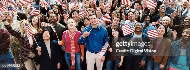 large crowd of people holding stars and stripes flags - american flag clothes imagens e fotografias de stock