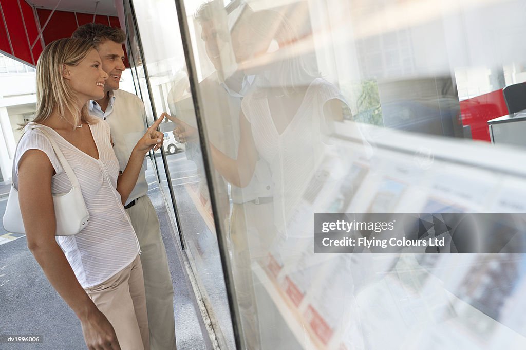 Couple Stand Outside an Estate Agents Looking at the Window Display