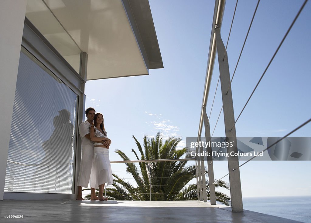 Couple Standing on a Coastal Apartment Balcony Looking at the View