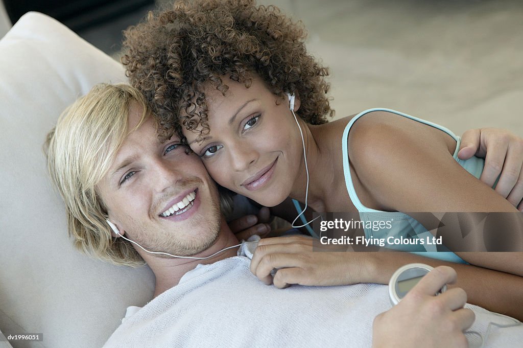 Couple Lying on Sofa and Sharing Headphones, Man Holding MP3 Player