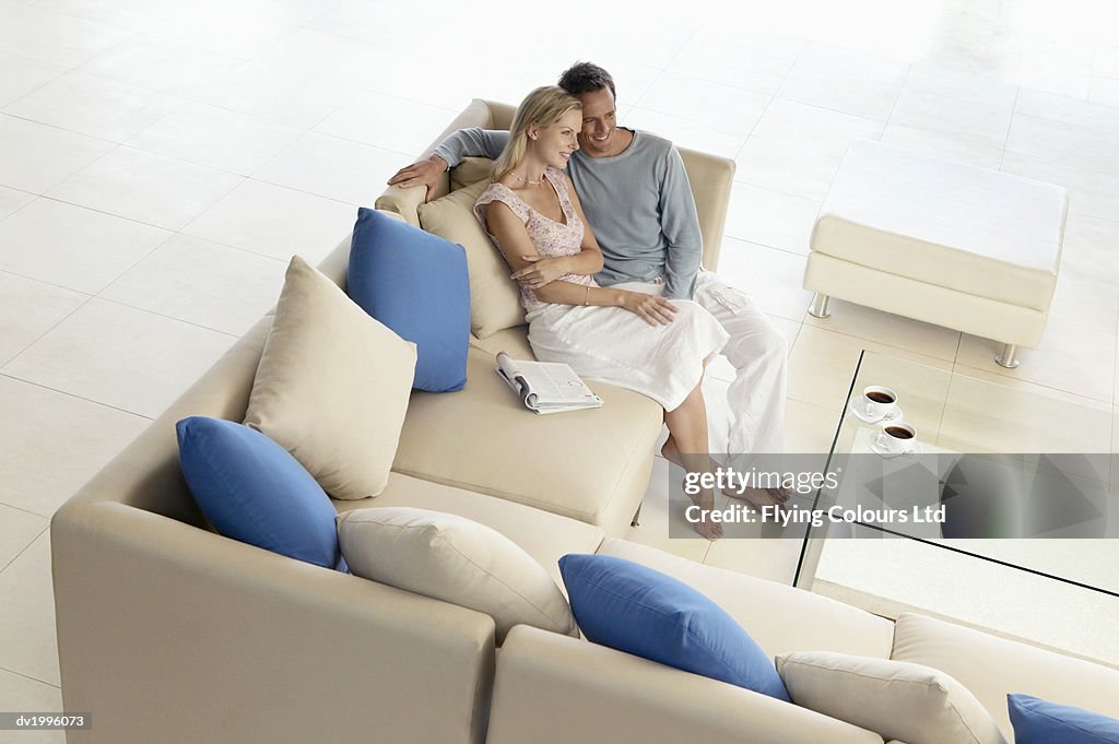 Thirty something Couple Sitting Side By Side on a Sofa