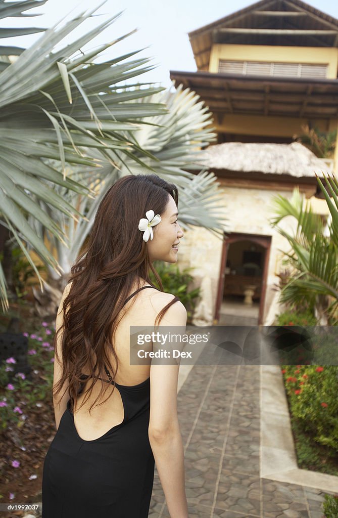 Rear View of a Woman Wearing a Flower in Her Hair and Walking Towards a Building