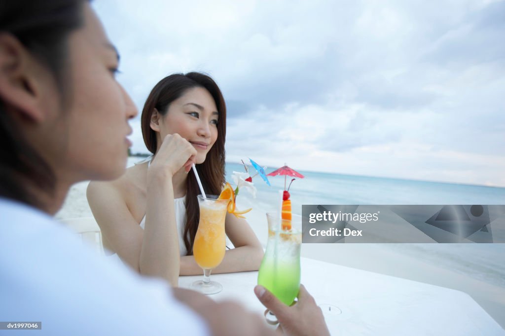 Couple Enjoying Cocktails at a Table on a Beach