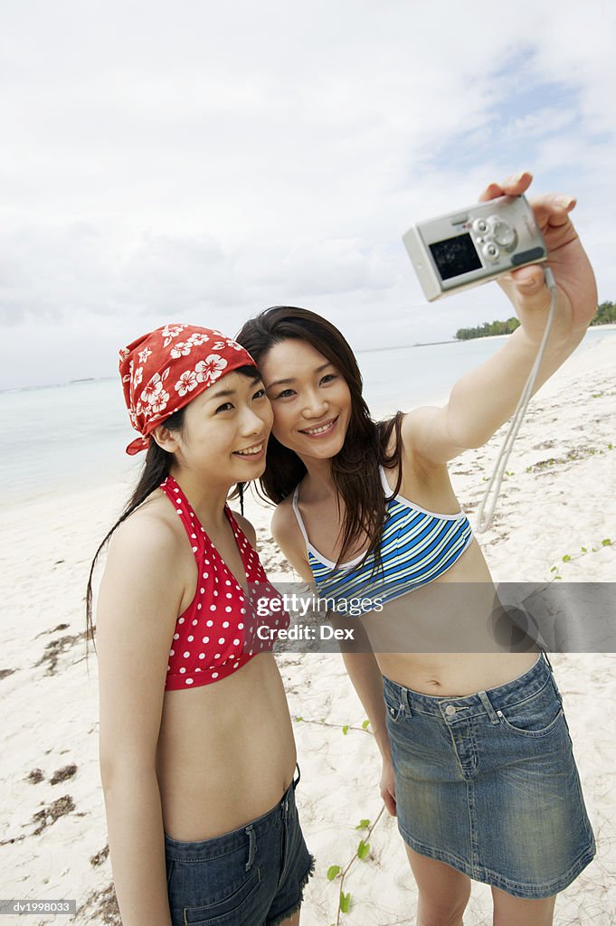 Two Young Women Taking a Self Portrait on the Beach With a Digital Camera