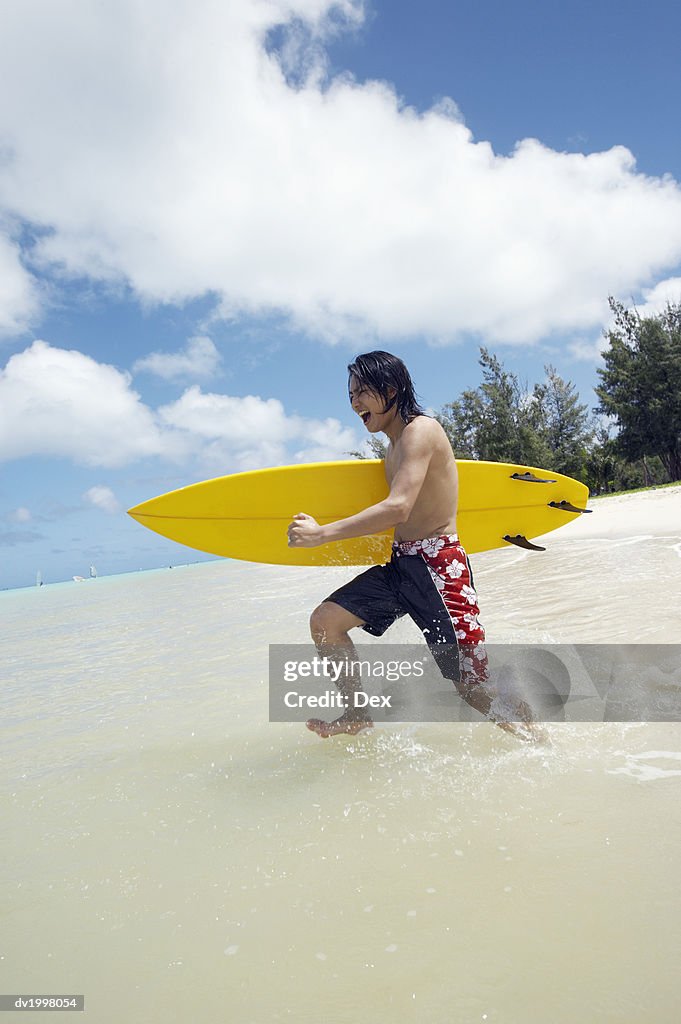 Young Man Running in the Sea and Carrying a Windsurfing Board