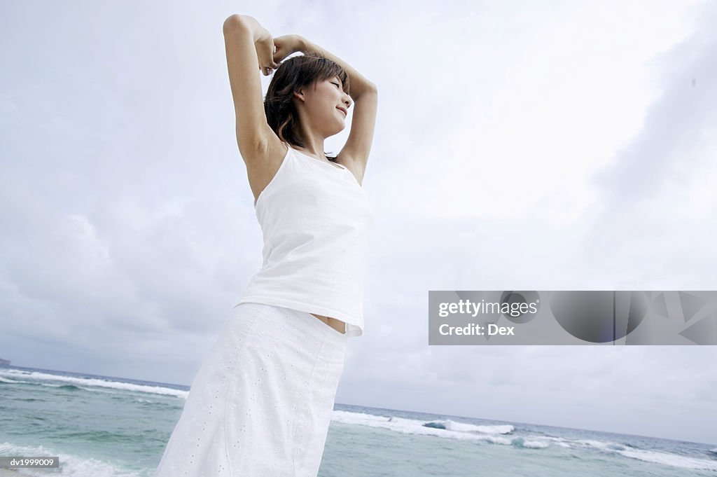 Woman Standing on a Beach With Her Arms Up