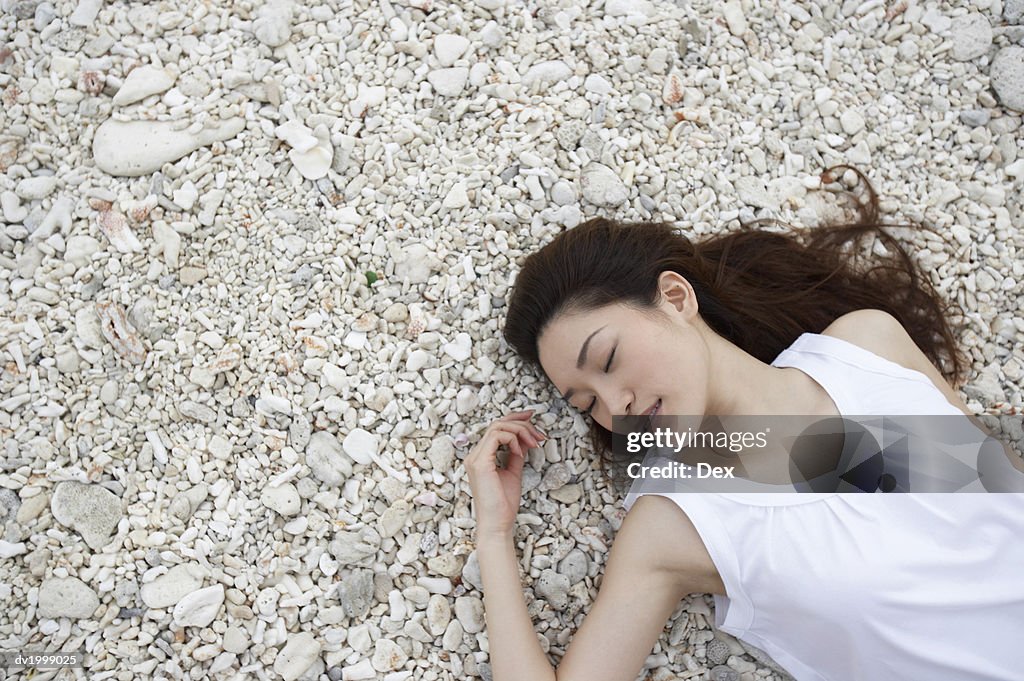 Elevated View of a Woman Lying on Pebbles With Her Eyes Closed