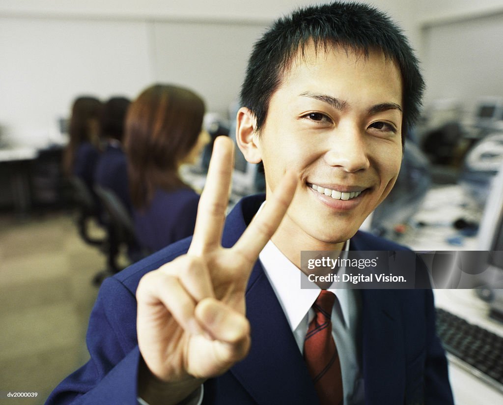 Portrait of a Schoolboy Making a Peace Sign, in a Computer Room