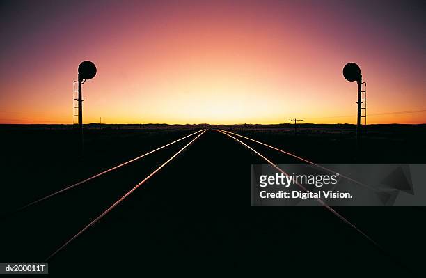 railroad track at sunset disappearing into a vanishing point - sunset point stock pictures, royalty-free photos & images