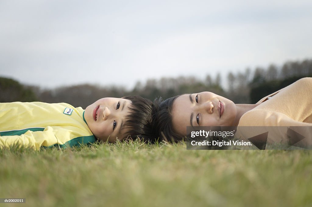 Surface Level Shot of a Mother and Son Lying Head to Head on Grass