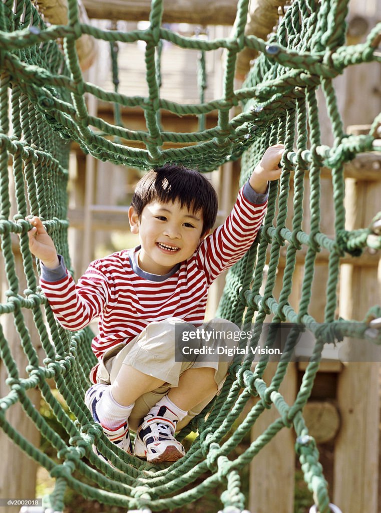 Young Boy Playing on Climbing Ropes in an Adventure Playground
