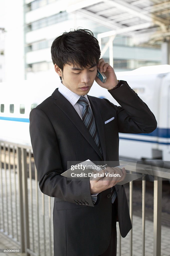 Businessman Holding a Mobile Phone and Looking at a Diary