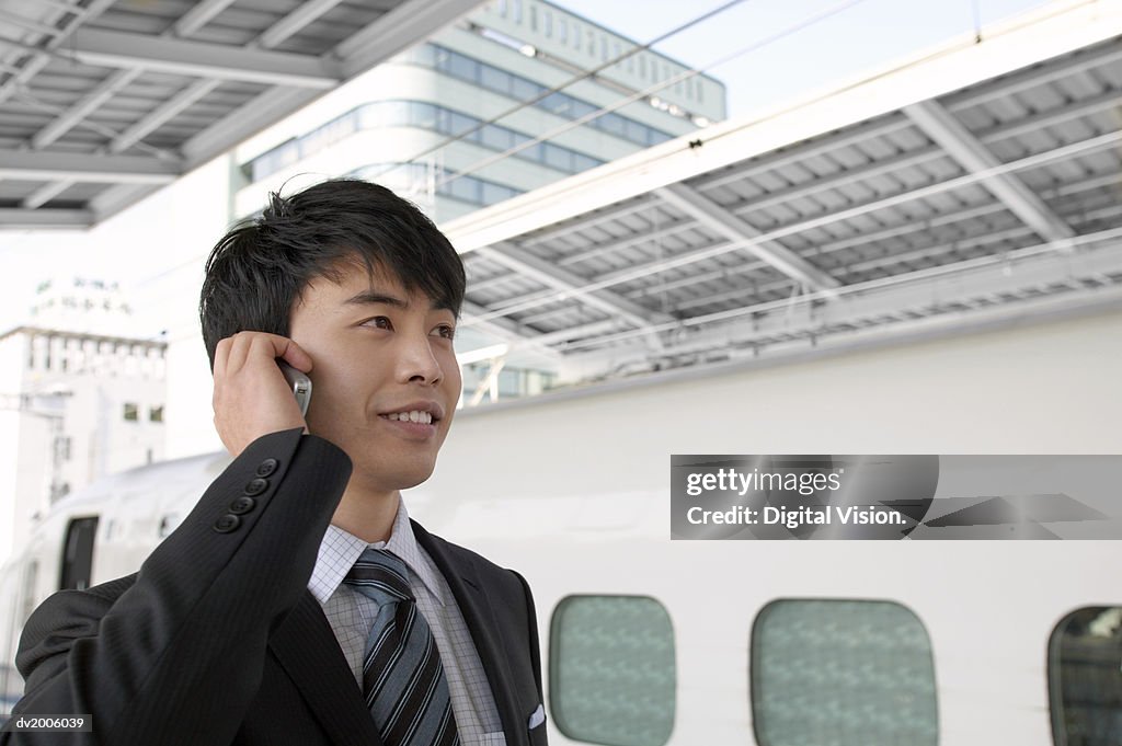 Businessman at a Train Station Using a Mobile Phone