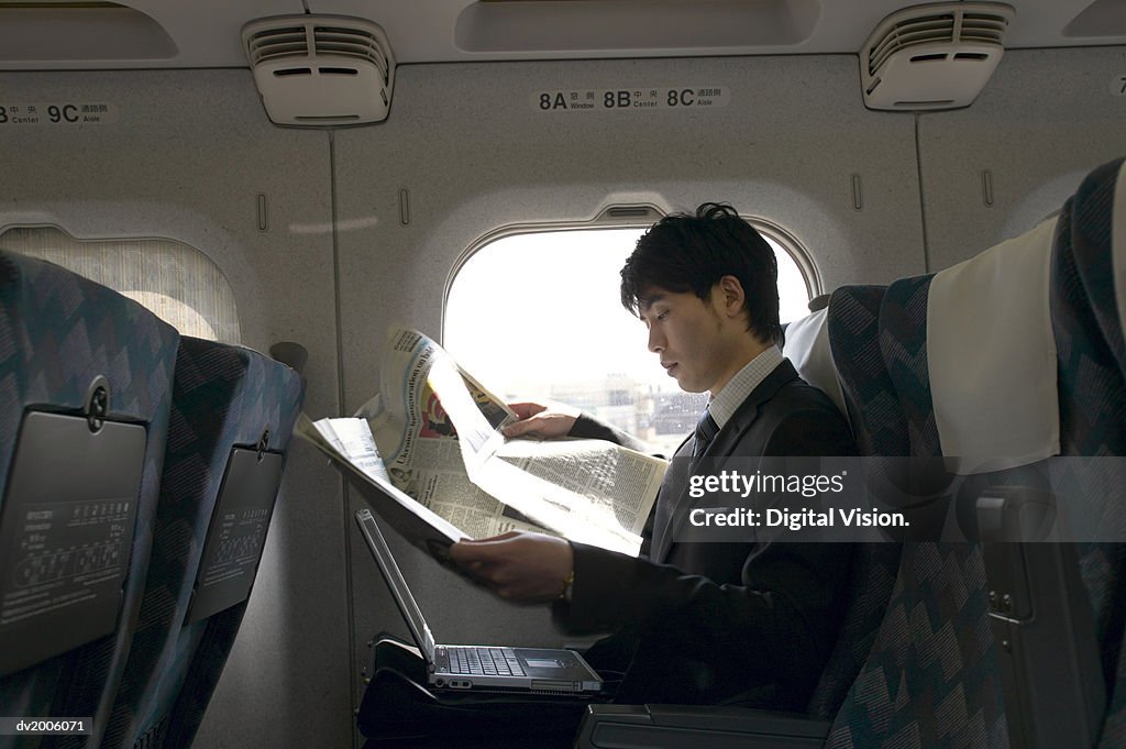 Businessman Sitting in a Passenger Train and Reading a Newspaper