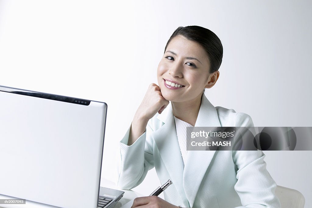 Portrait of a Businesswoman With Her Hand on Her Chin Sitting by a Laptop