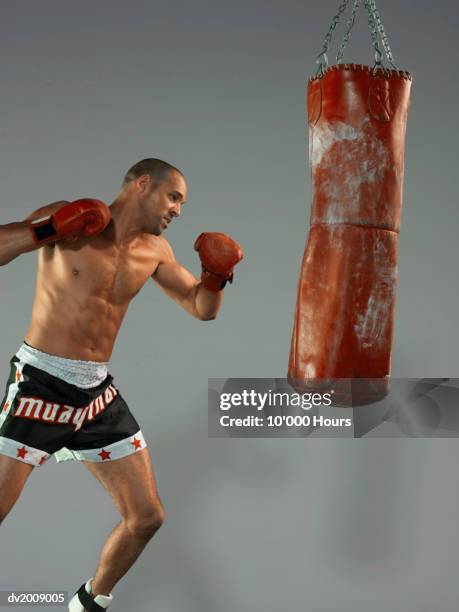 male boxer punching a punch bag - boksbroek stockfoto's en -beelden