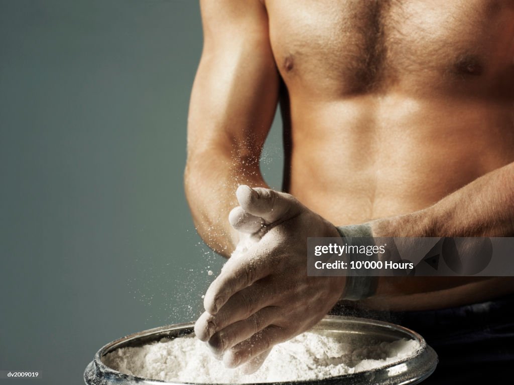 Mid Section View of Male Athlete Applying Chalk to His Hands