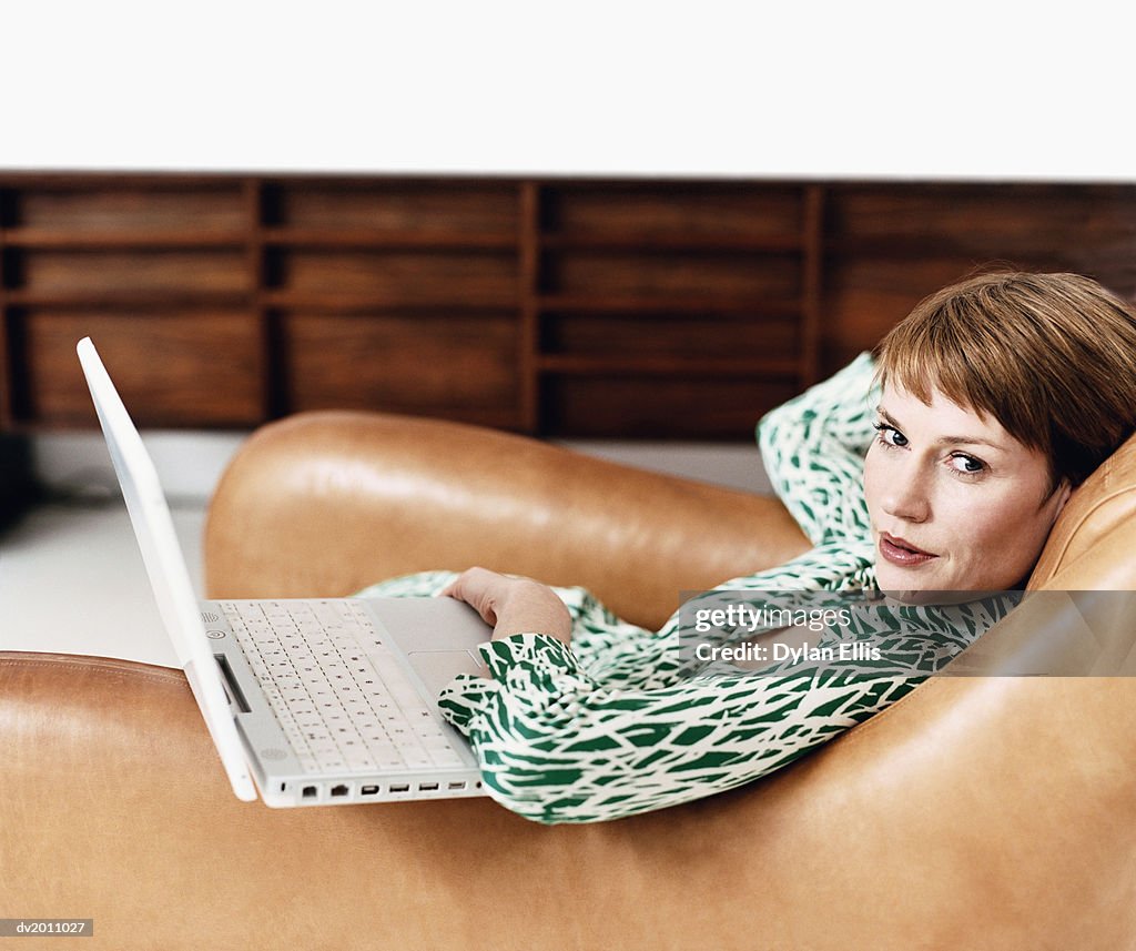 Woman Sitting in an Armchair With a Laptop