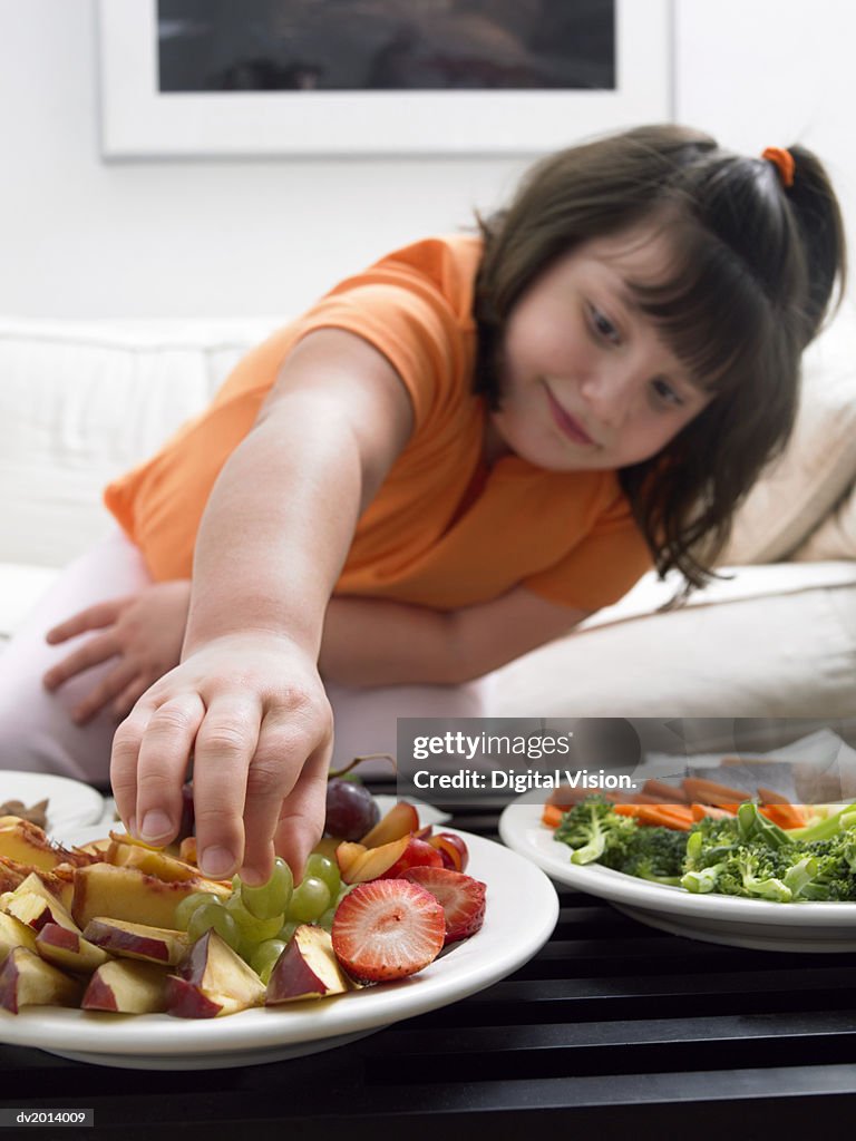 Girl Choosing a Grape from a Plate of Fruit