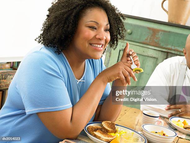 thirtysomething woman eating fruit at a table in the morning - negligée stock-fotos und bilder