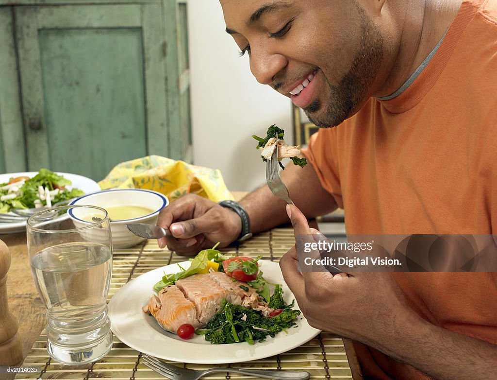 Man Sits at a Table at Home Eating a Salmon Salad for Lunch