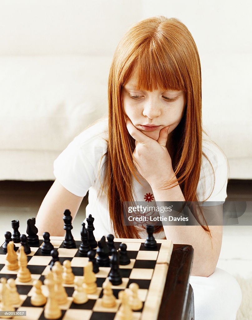 Young Girl Concentrating on a Chess Board