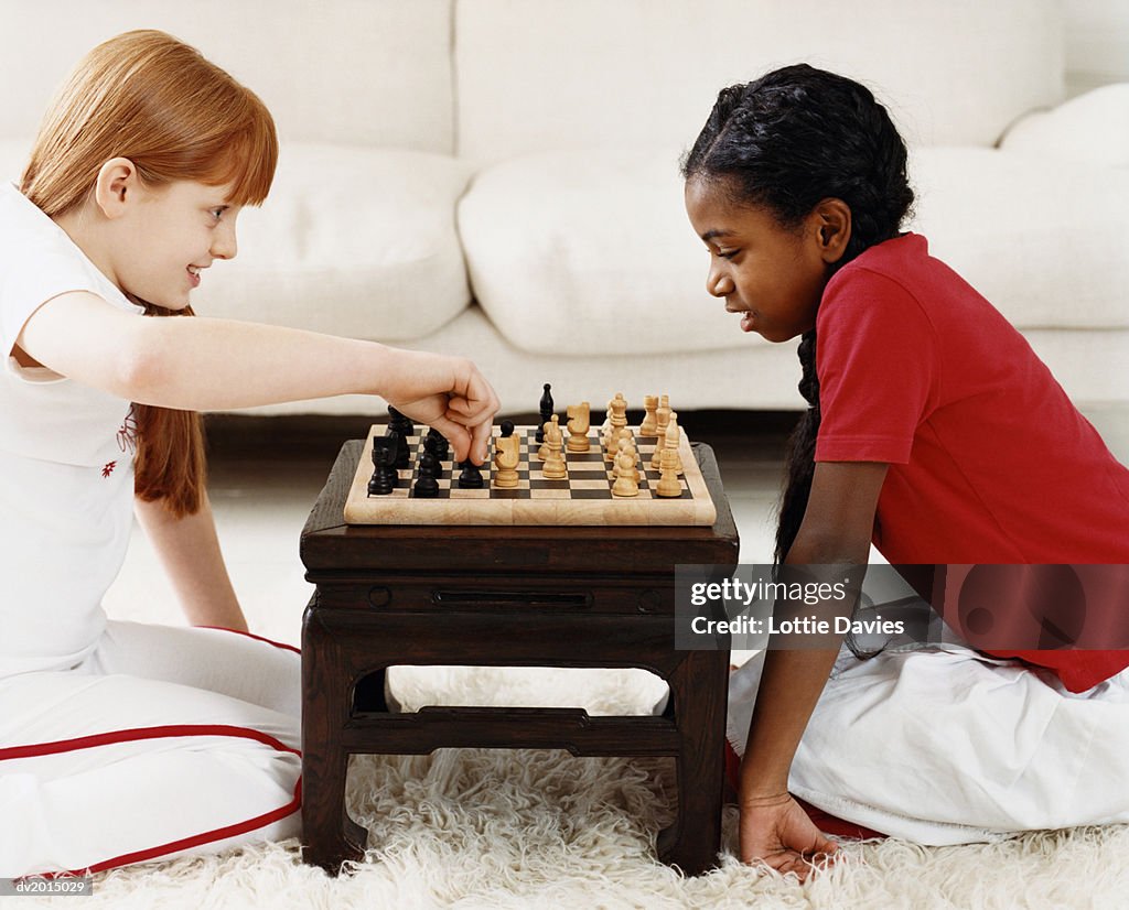 Two Girls Playing a Game of Chess in a Living Room