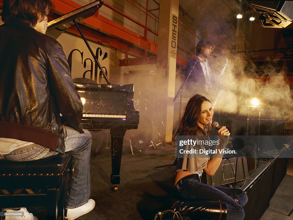 Female Singer Performs on Stage With a Male Pianist and Saxophonist