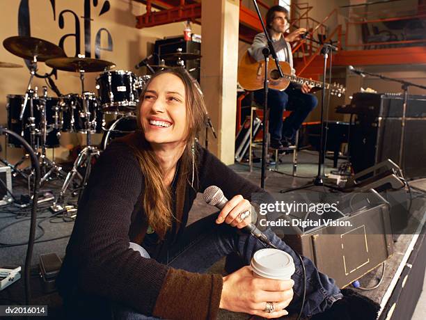 female singer sits on a stage having a coffee break at a gig rehearsal - ensayo fotografías e imágenes de stock