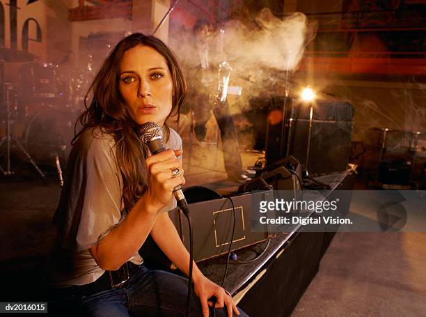 young female singer performs with a band on a smokey stage - gesangskunst stock-fotos und bilder