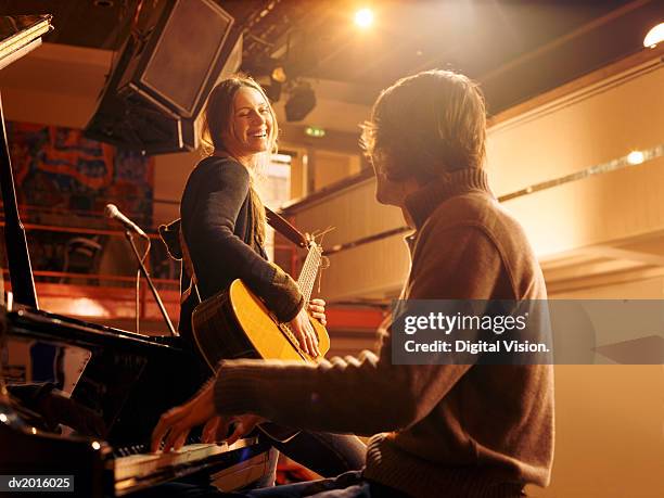 woman holding an acoustic guitar leaning against a piano and smiling at a male pianist - the sag aftra foundations conversations series presents mark ruffalo of spotlight stockfoto's en -beelden