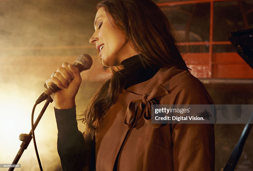 Female Singer Singing into a Microphone on a Smokey Stage