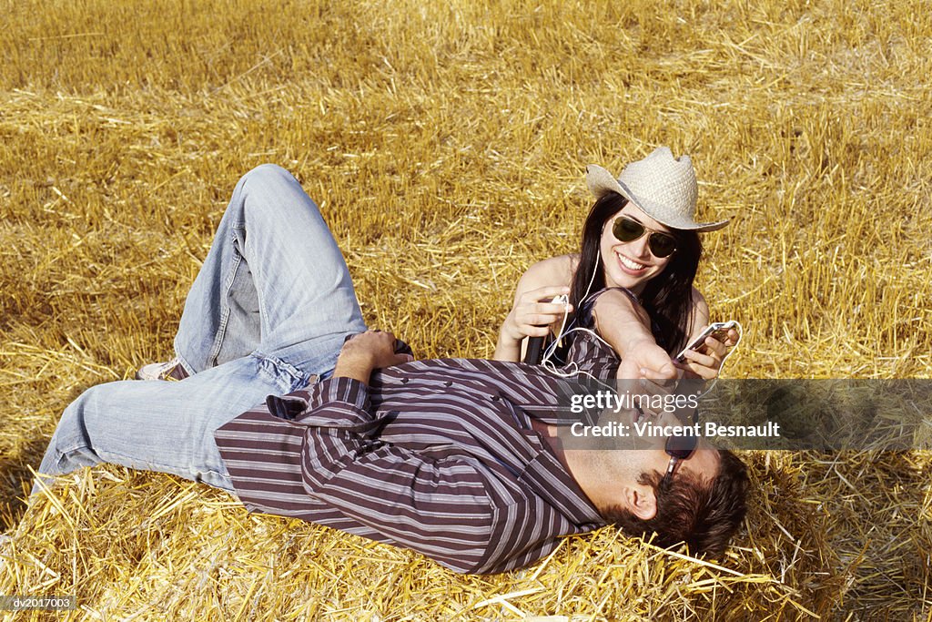 Couple Relaxing on Bales of Hay and Listening to an MP3 Player