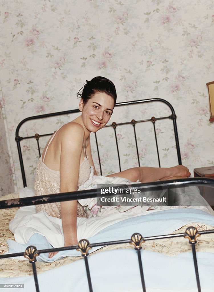 Woman Wearing a Dress Sitting on a Bed
