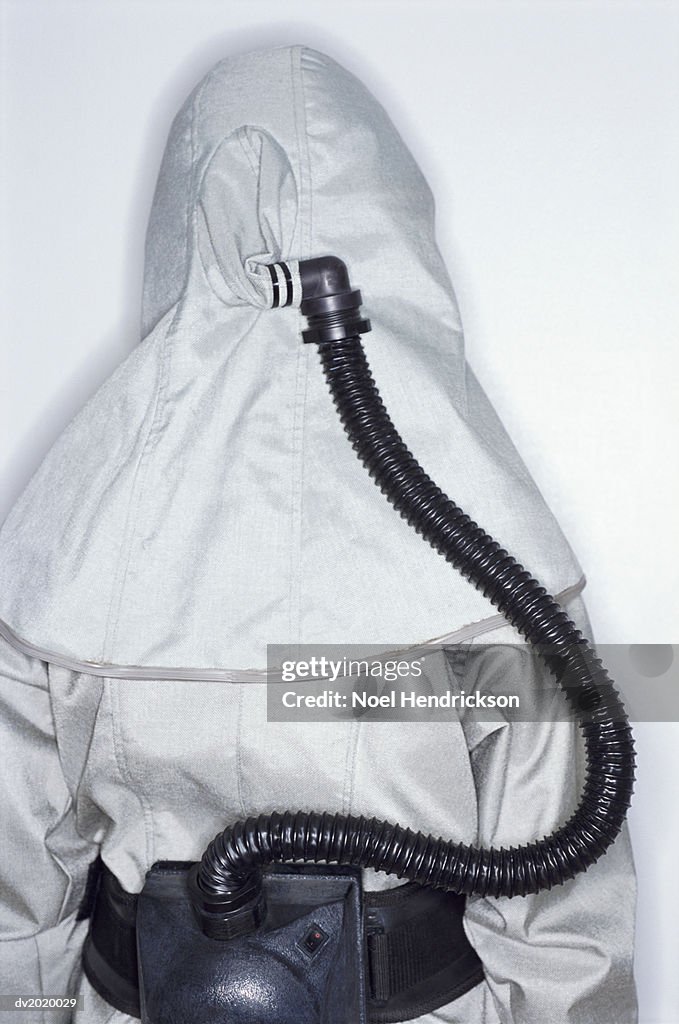 Rear View of an Unrecognizable Person Wearing a Protective Suit with a Tube Attached to a Hood