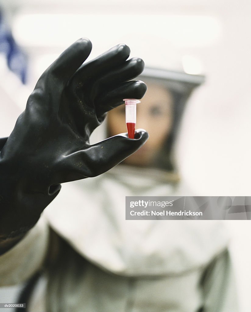 Woman Dressed in Protective Mask and Clothing and Holding a Blood Sample