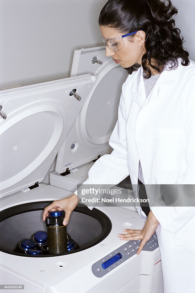 Lab Technician Inserting a Bottle Into a Centrifuge