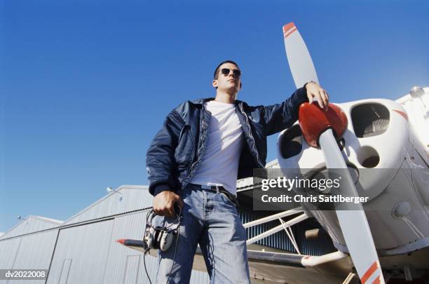 pilot standing by a propeller aeroplane - pilot jacket stockfoto's en -beelden