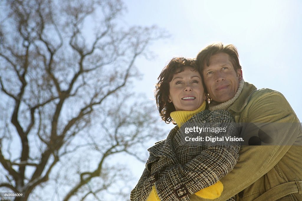 Low Angle View of a Mature Couple in Winter Coats Standing Outdoors Embracing