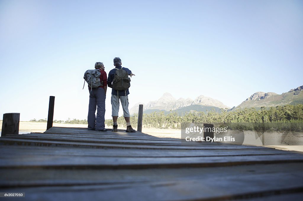 Low Section Shot of a Mature Couple Standing on a Pier, Wearing Back Packs