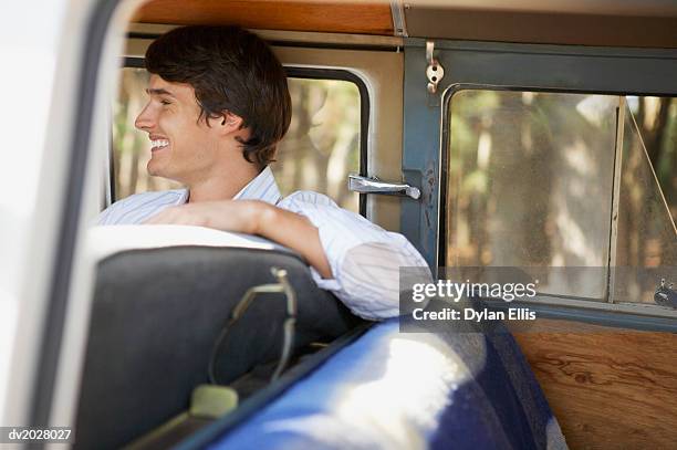 smiling young man sitting in the front seat of a motor home - ellis stock-fotos und bilder