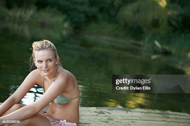 young woman sitting on a wooden jetty on a lake - ellis stock-fotos und bilder