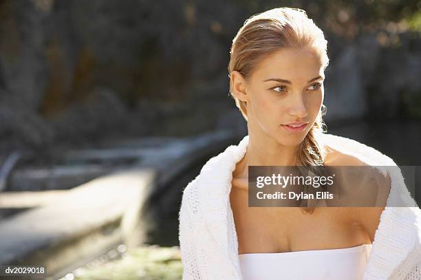 young woman wearing a bikini top and a cardigan looking sideways - ellis stock-fotos und bilder