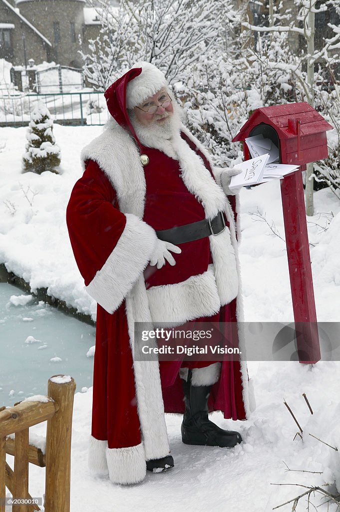 Father Christmas in a Garden Collecting Mail from a Mail Box