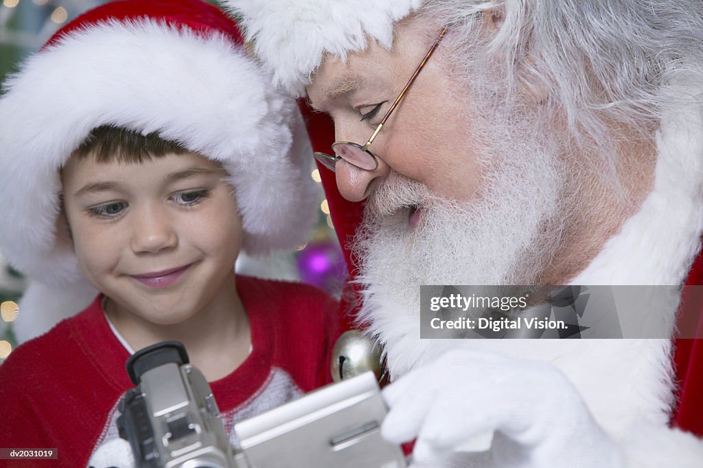 Santa Claus and Young Boy Looking at a Camcorder